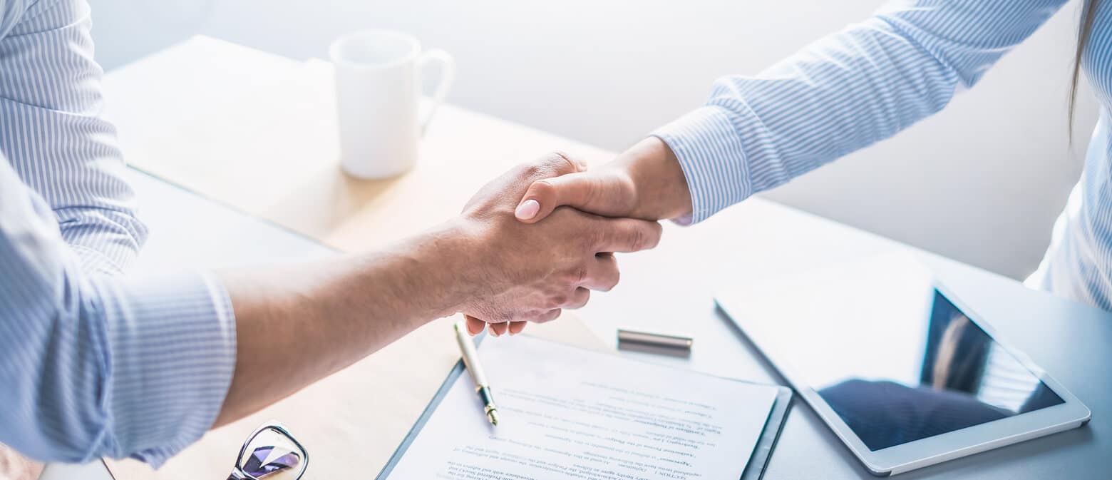 The general counsel of a company shakes hands with their new ALSP representative after learning how to choose an ALSP partner.